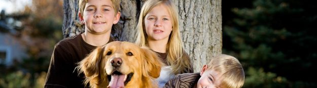 Kinder mit ihrem Hund vor einem Baum