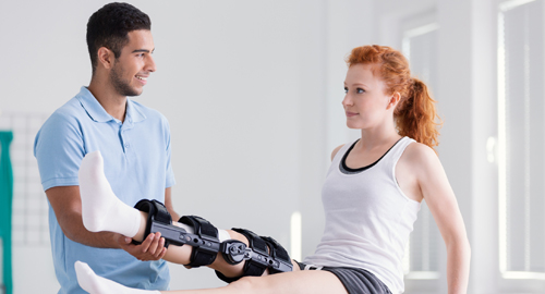 Physiotherapeut macht Bein-Übungen mit Frau